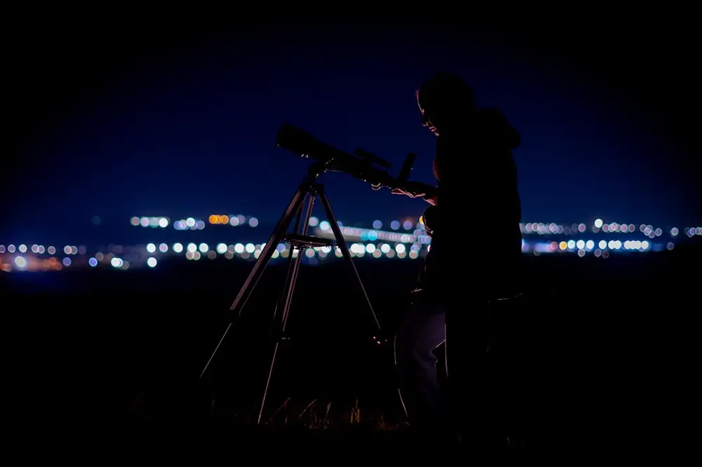 Persona observando con un telescopio de noche